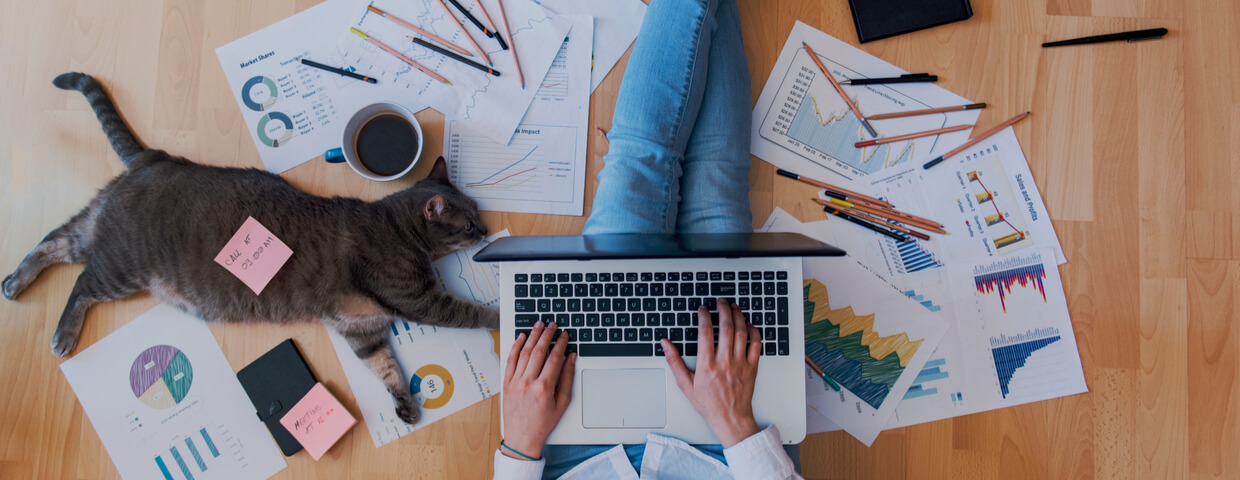 Someone working from home, while sitting on floor with papers spread out around them.