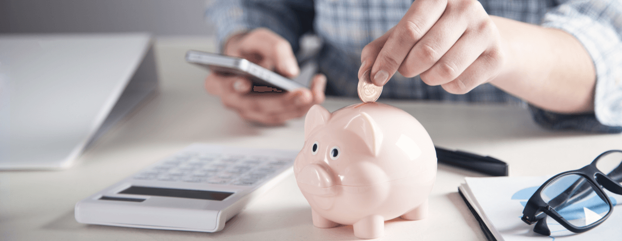 Woman hold phone and placing coin into piggy bank.