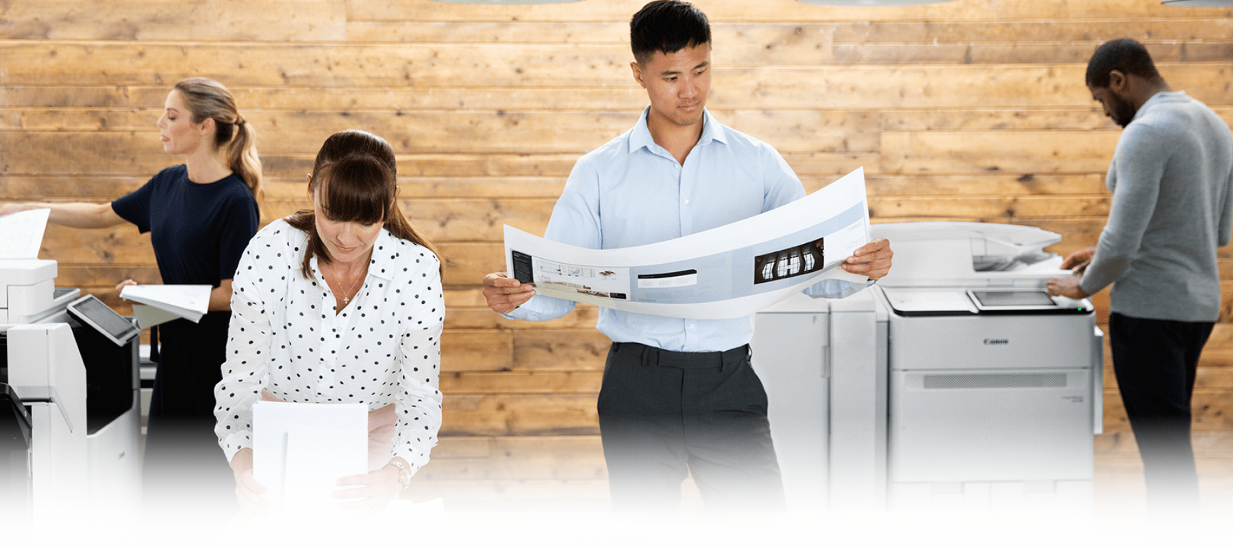 Man in an office looking over a large printed document.