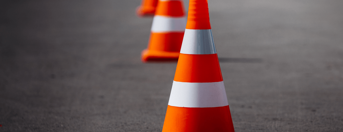 bright orange traffic cones standing in a row on dark asphalt
