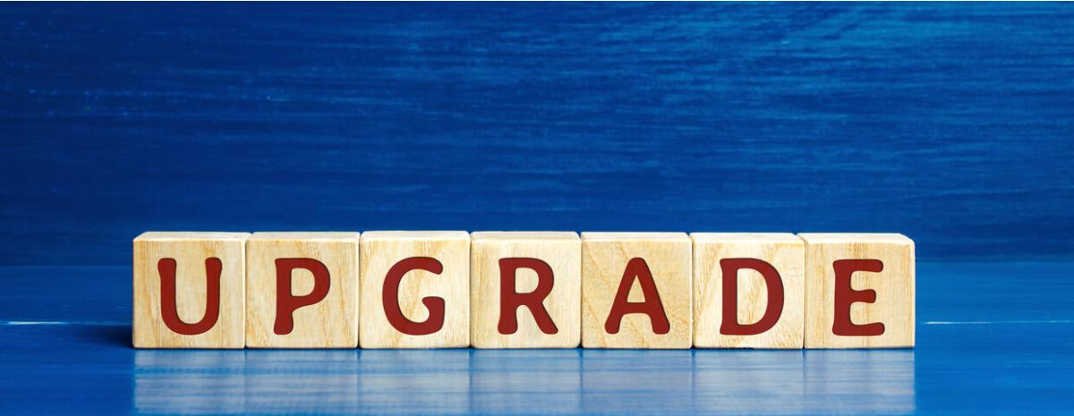 Wooden blocks that spell out the word upgrade in red letters on a blue surface with a blue background