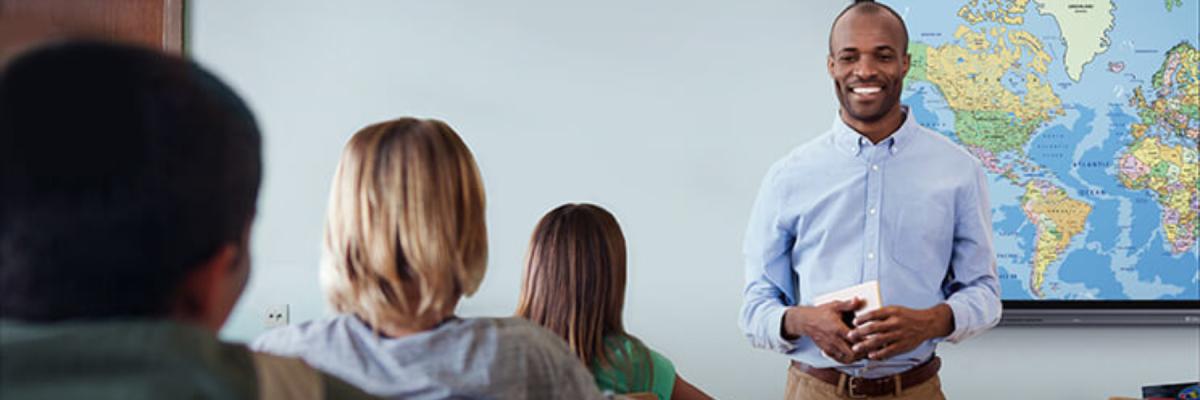 Male teacher or professor standing in front of a classroom of students in front of a whiteboard, education concept