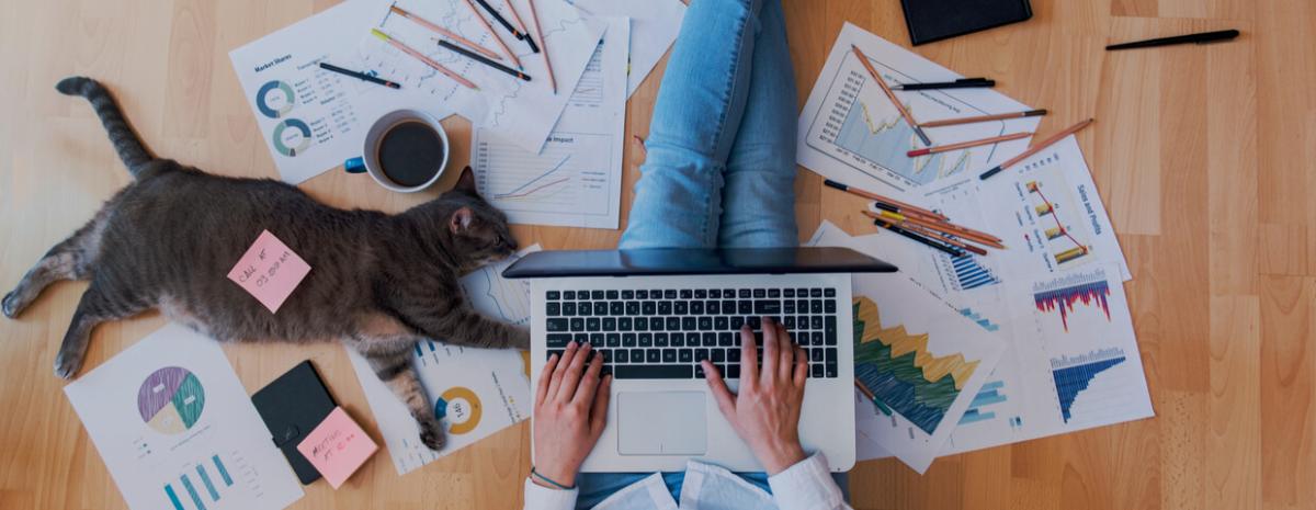 Someone working from home, while sitting on floor with papers spread out around them.