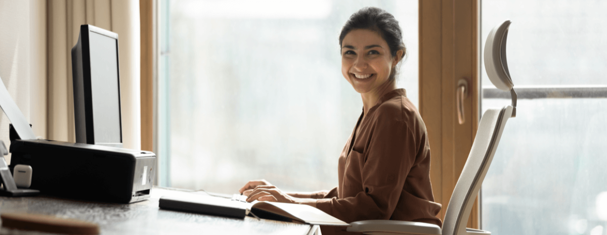 Young woman smiling, sitting on chair at office desk.
