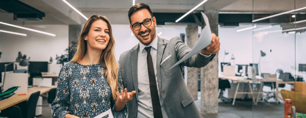 Two business employees walking through open office space.