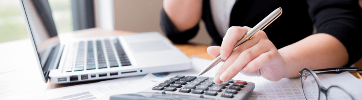 close up of an accountant working on a laptop with a calculator on the desk