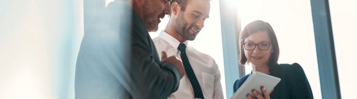 close up of coworkers talking about a document, man holding a document talking to another man and woman while at work