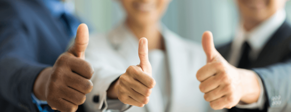 Three office employees smiling and holding thumbs up.